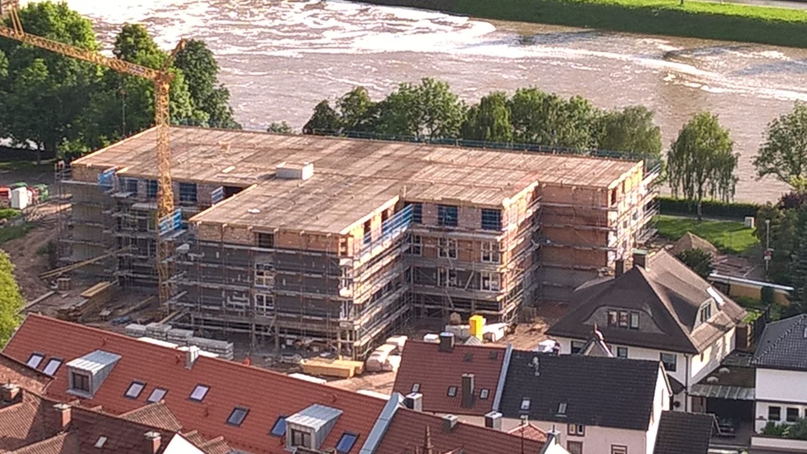 Gebäude im Bau mit Gerüst am Fluss, Luftaufnahme.