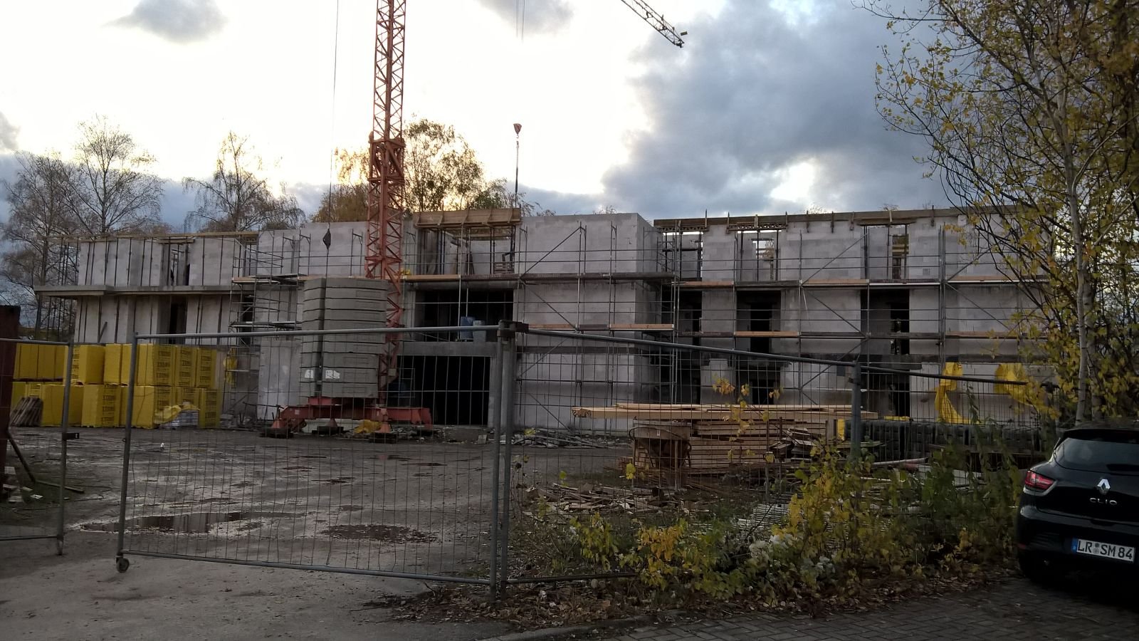 Betonstruktur mit Gerüst und Kran in der Abenddämmerung.
