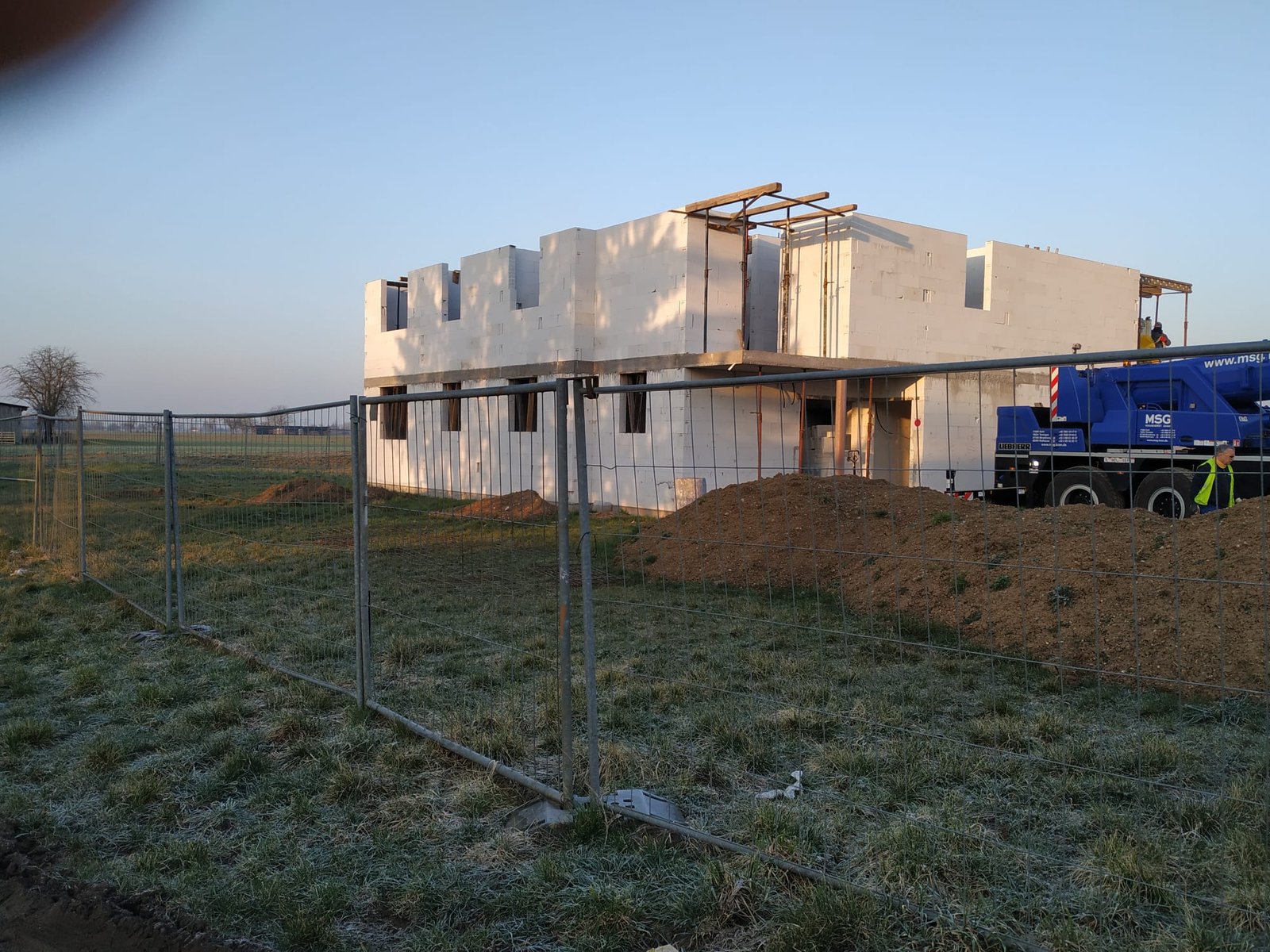 Rohbau eines Gebäudes mit Kran im Morgenlicht.